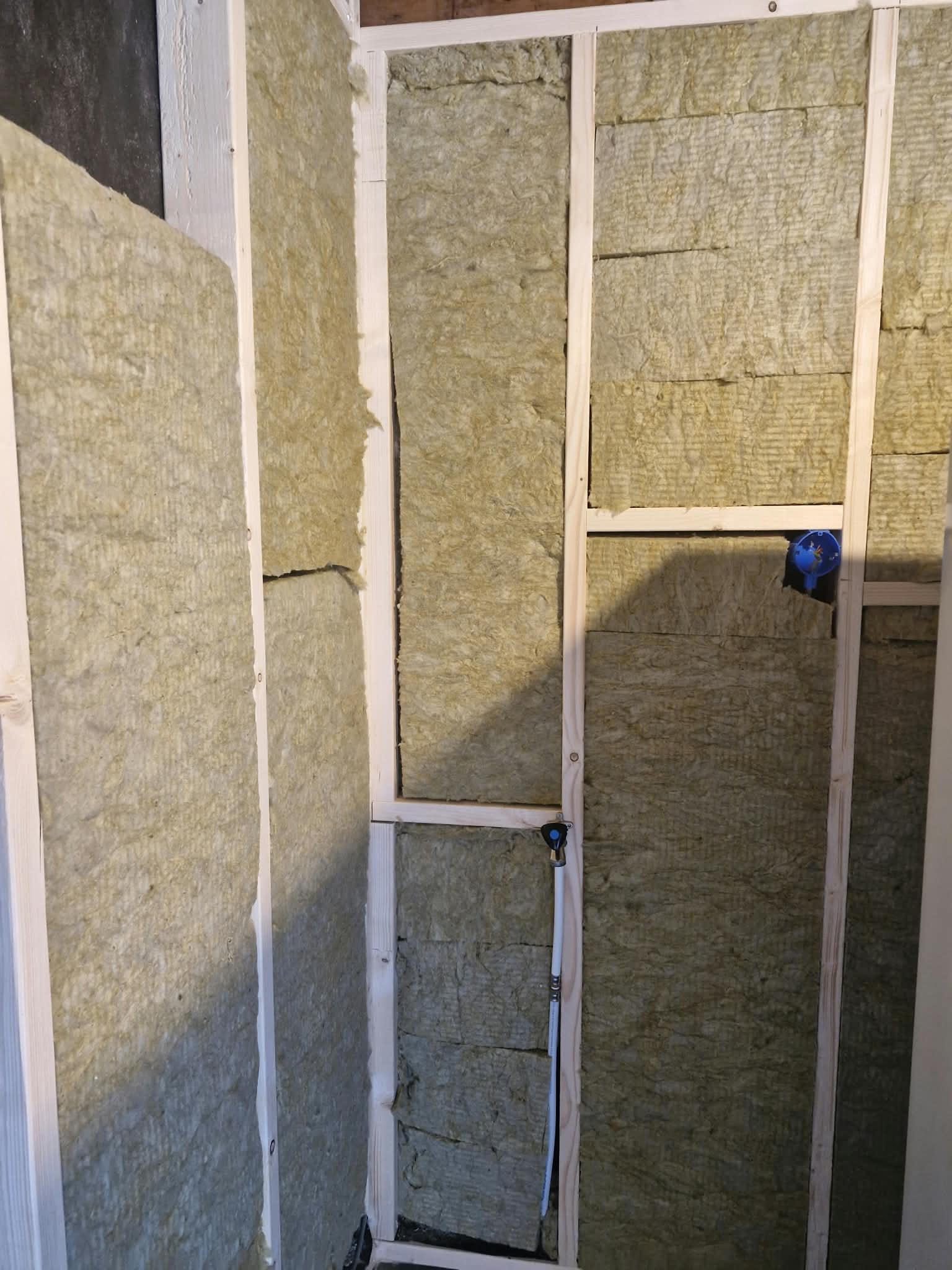 Steenwolisolatie tussen het houten frame met waterleiding en inbouwdoos