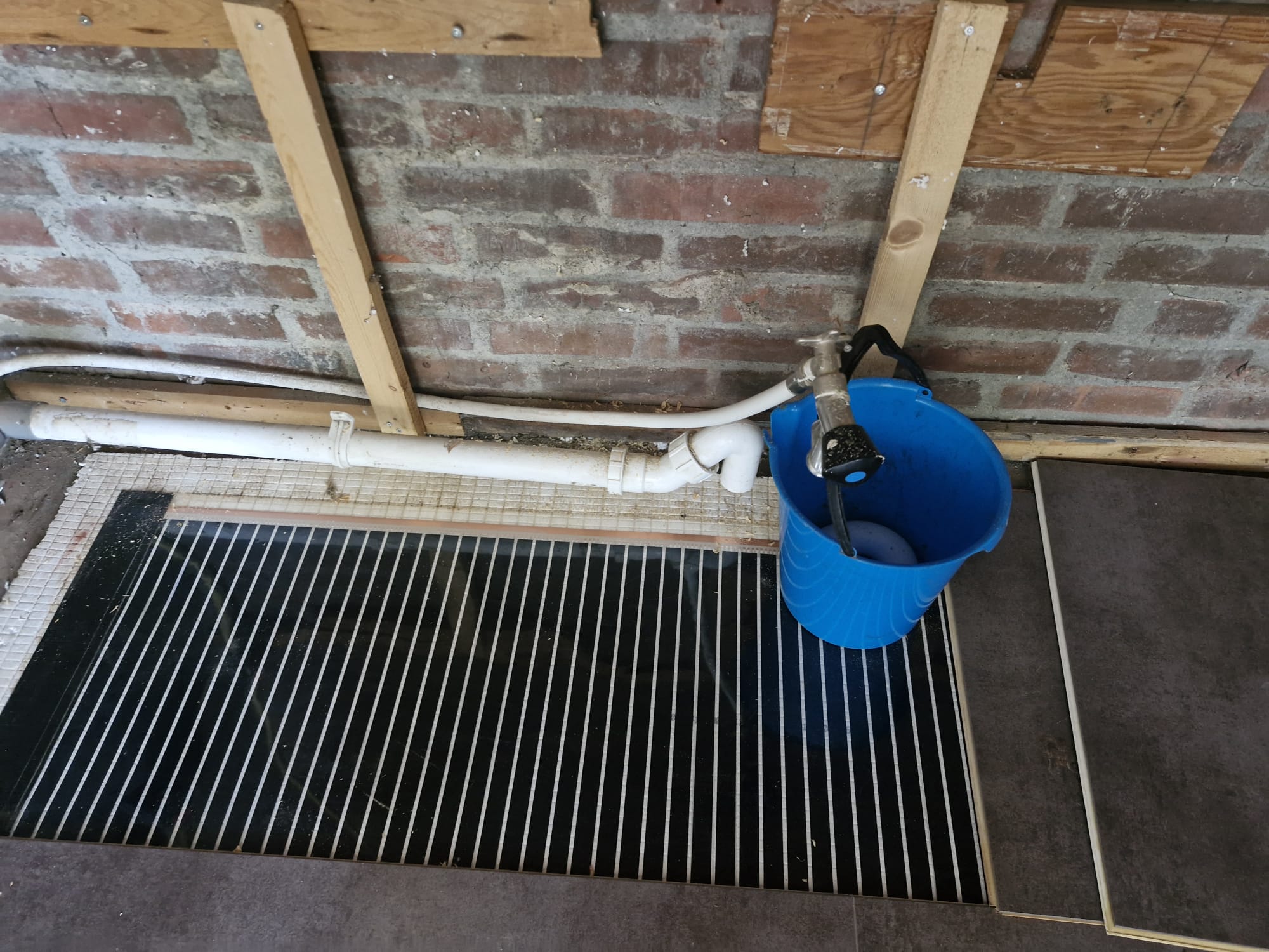 Elektrische vloerverwarming gelegd langs de afvoerleiding