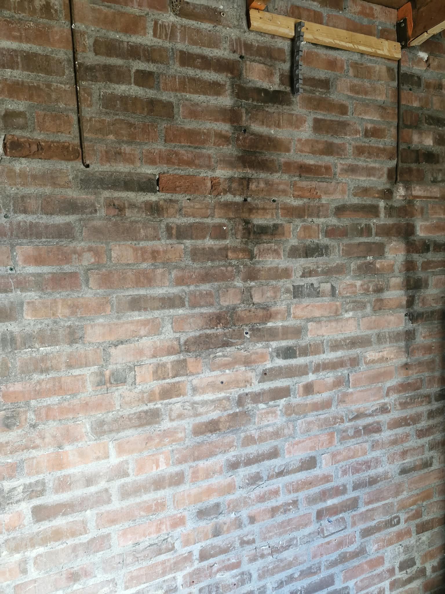 Voor: kale bakstenen muur met oude balken